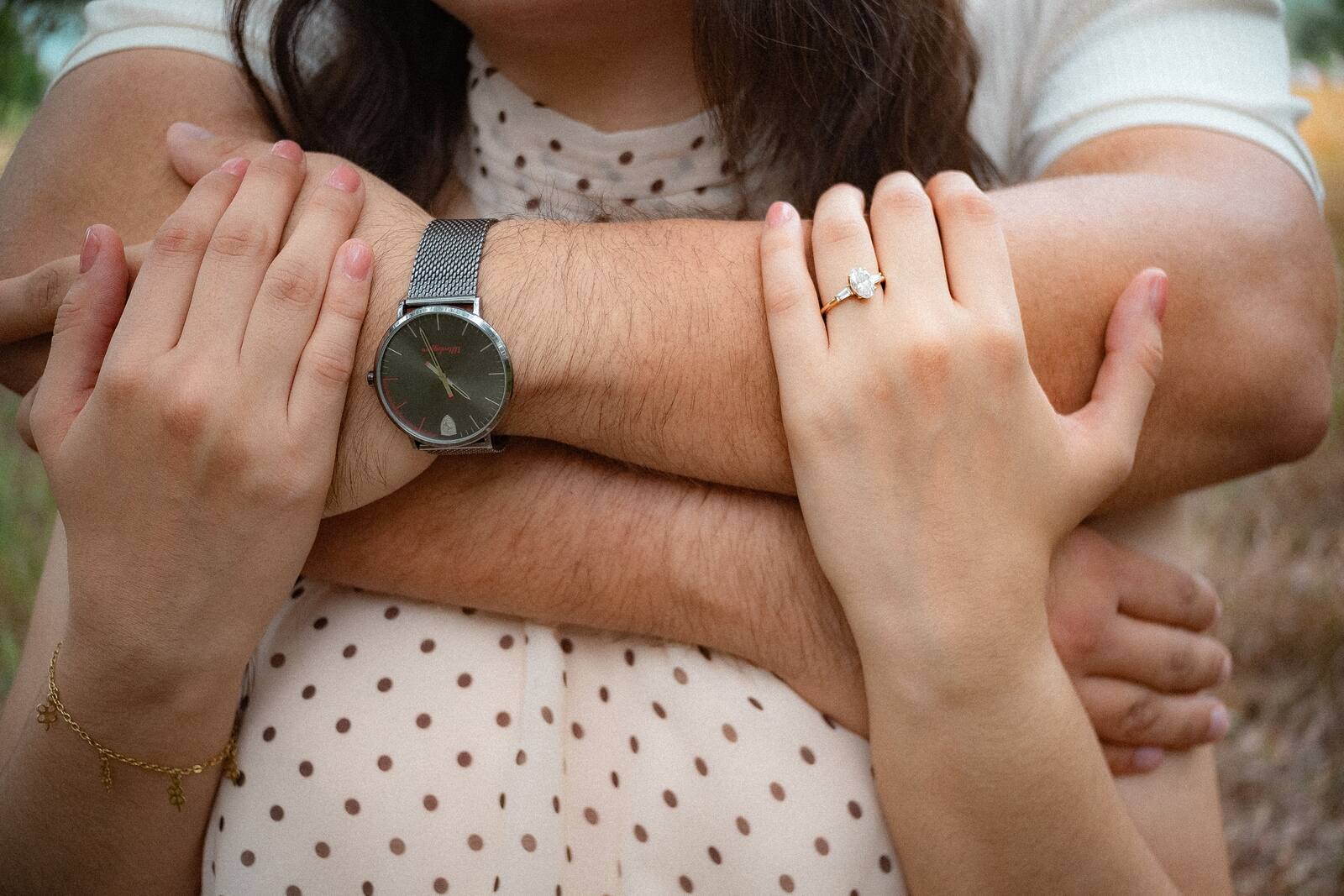 Las manos de Carolina y Brian entrelazadas, con el anillo y el reloj